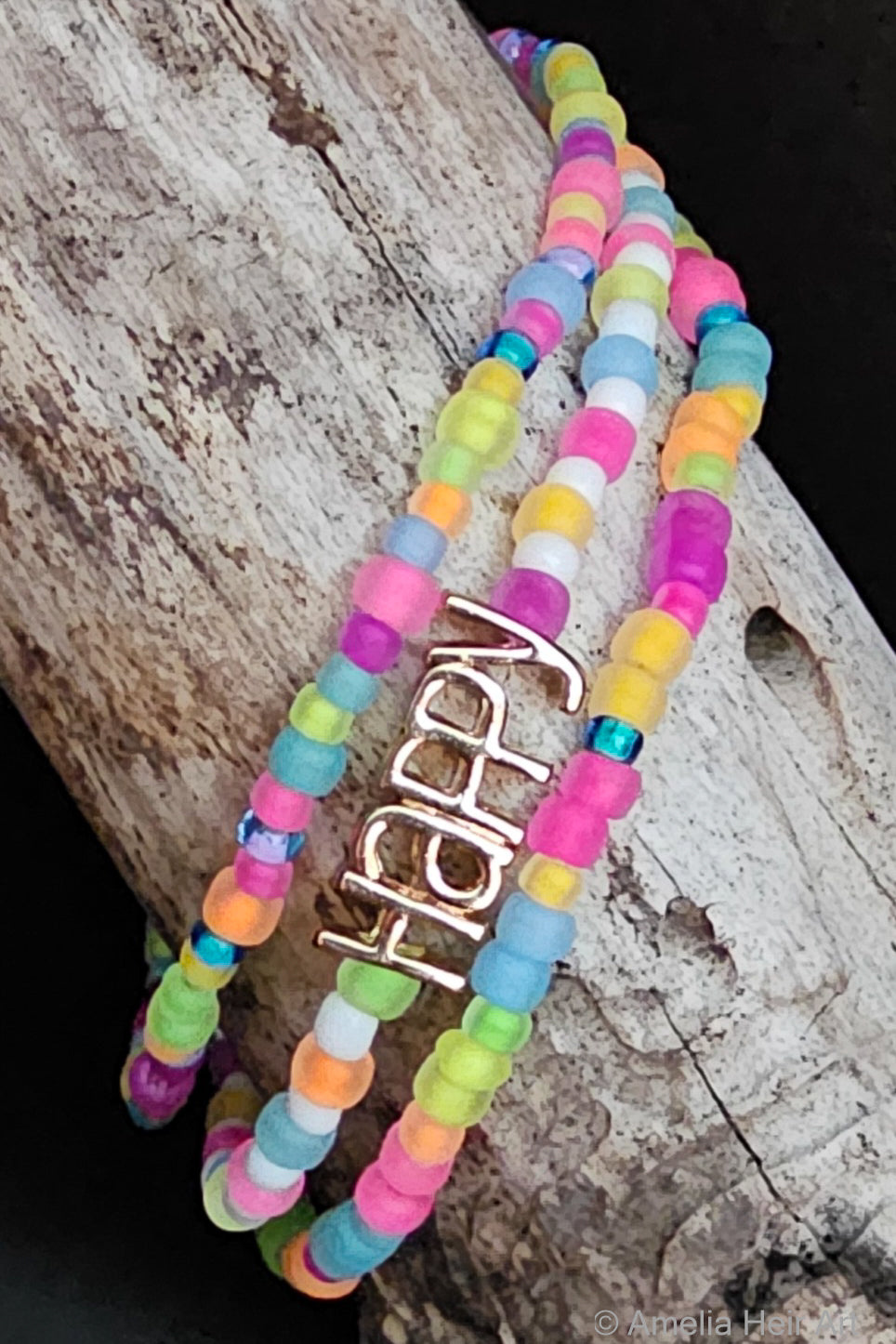 Happy Beaded Bracelet Set handcrafted full-spectrum fluorescent beaded bracelet set with HAPPY charm on a wooden surface — Amelia Heir Art