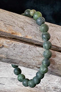 Green beaded bracelet on a wooden surface with a dark background