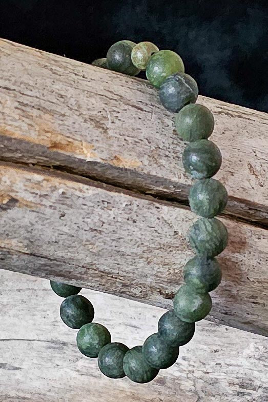 Green beaded bracelet on a wooden surface with a dark background