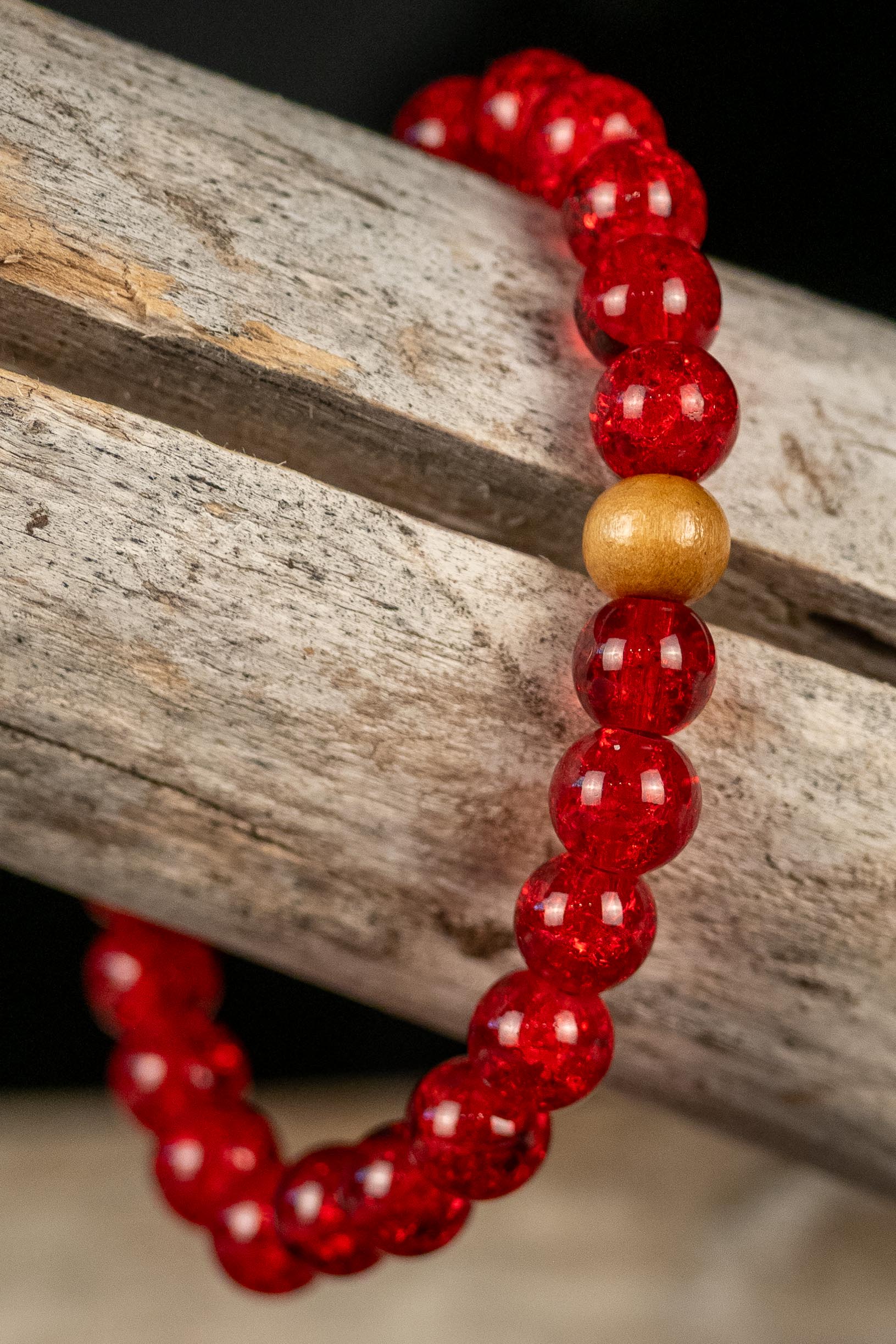 Red beaded bracelet with a wood bead on a wooden surface