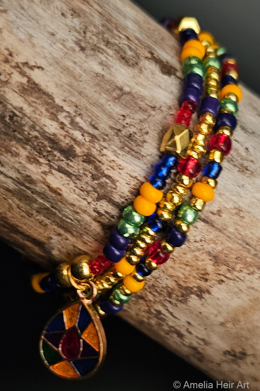 Colorful beaded bracelet with a gold charm on a wooden surface
