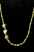 Necklace with green and cream heart-shaped beads on a black background