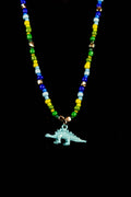 Necklace with colorful beads and a blue dinosaur charm on a black background