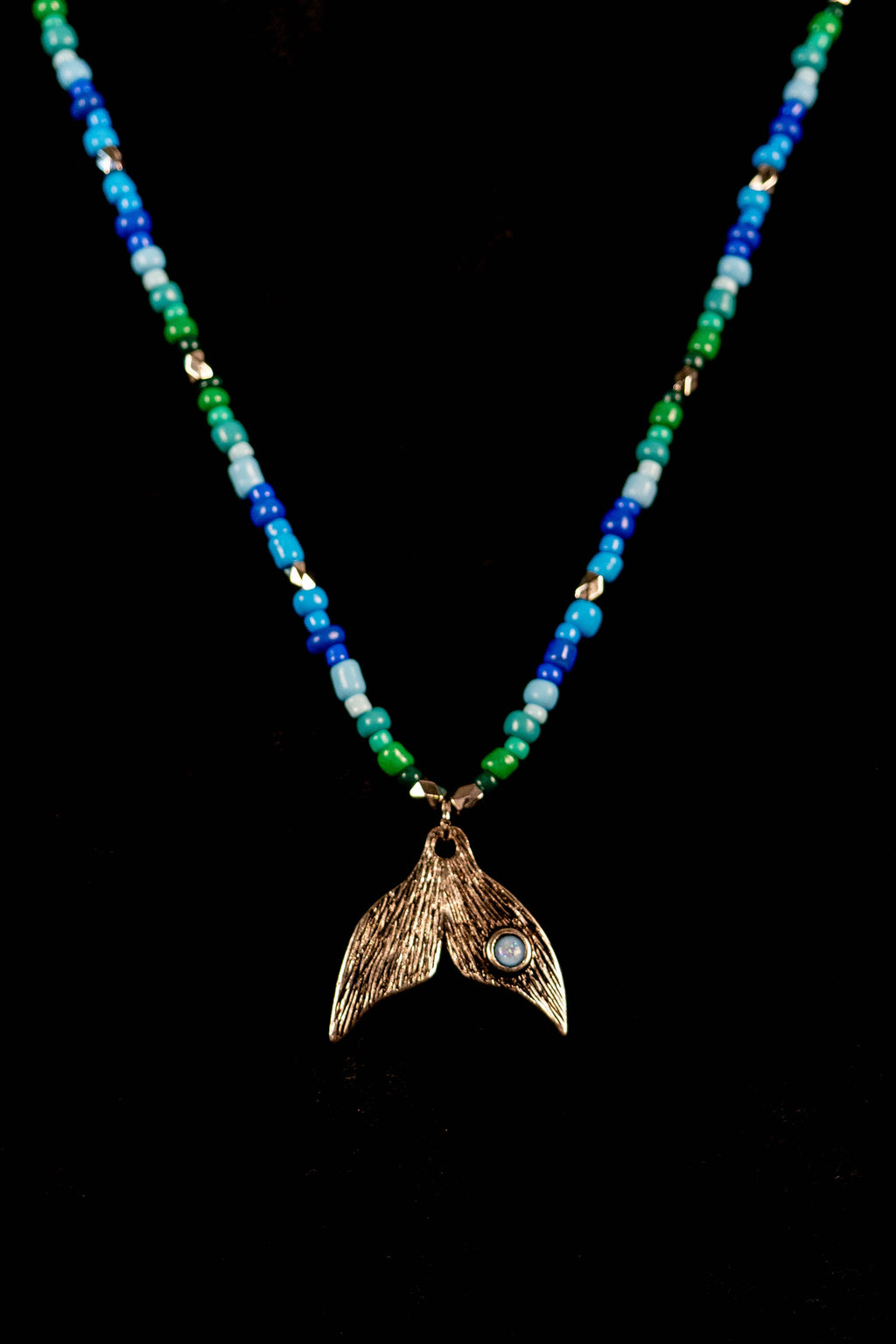 Necklace with a mermaid tail pendant on a black background