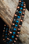 Beaded bracelets in black, blue, and copper on a wooden surface.