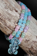 Multicolored beaded bracelets with a gummy-bear-shaped charm on a wooden surface