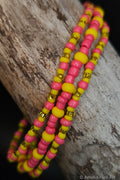 Pink and yellow beaded bracelets on a wooden surface