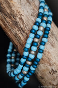 Stack of blue and gray beaded bracelets on a wooden surface