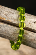 Green square beaded bracelet on a wooden surface