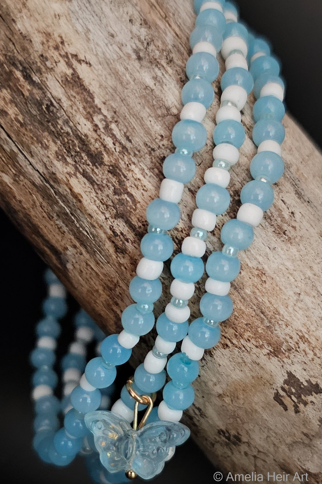 Blue and white beaded bracelets with a butterfly charm on a wooden surface