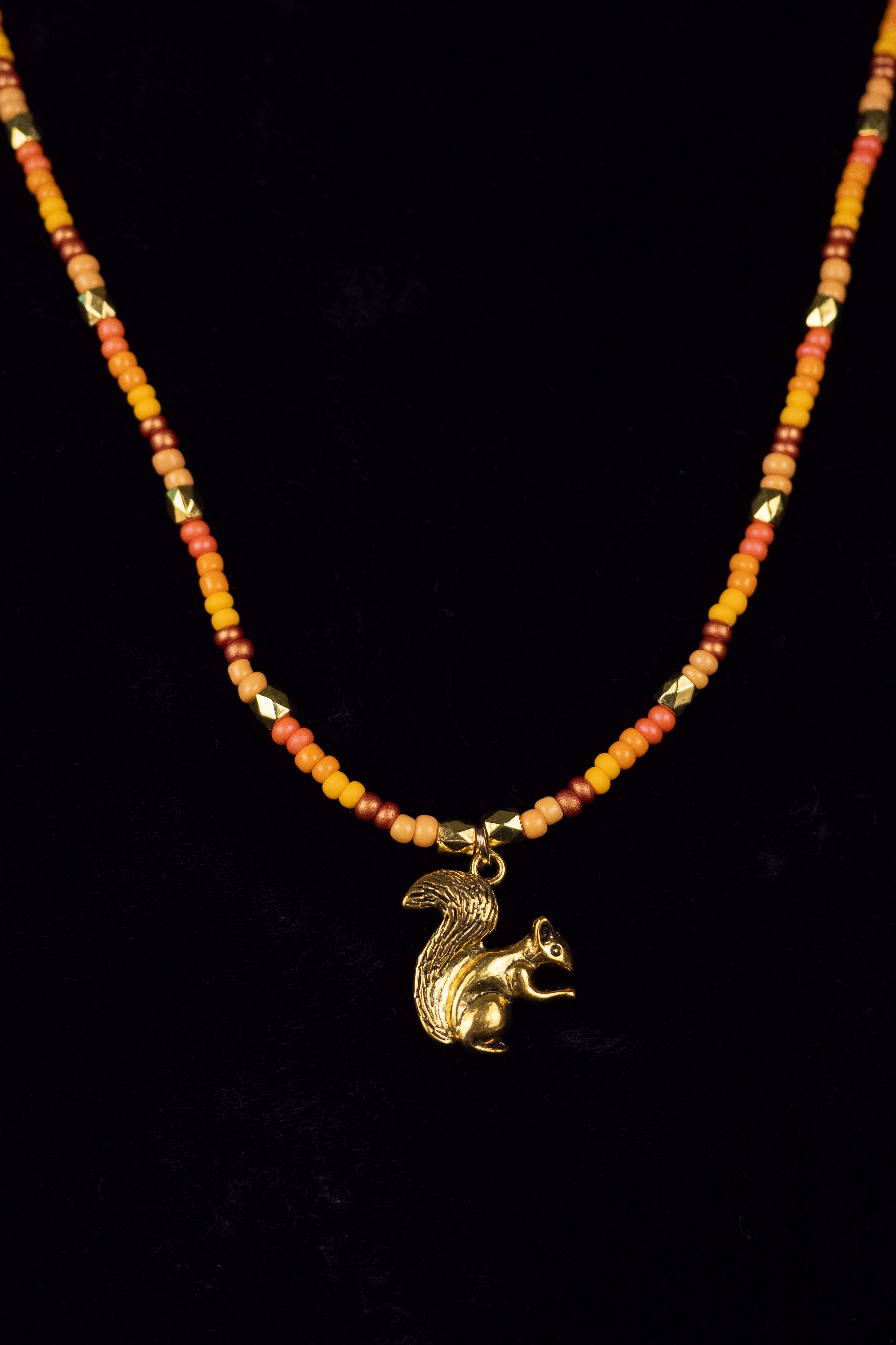 Necklace with a gold squirrel pendant on a black background