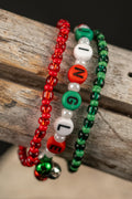 Three beaded bracelets in red, green, and white with the word 'JINGLE' and three tiny ingle bells on a wooden surface.