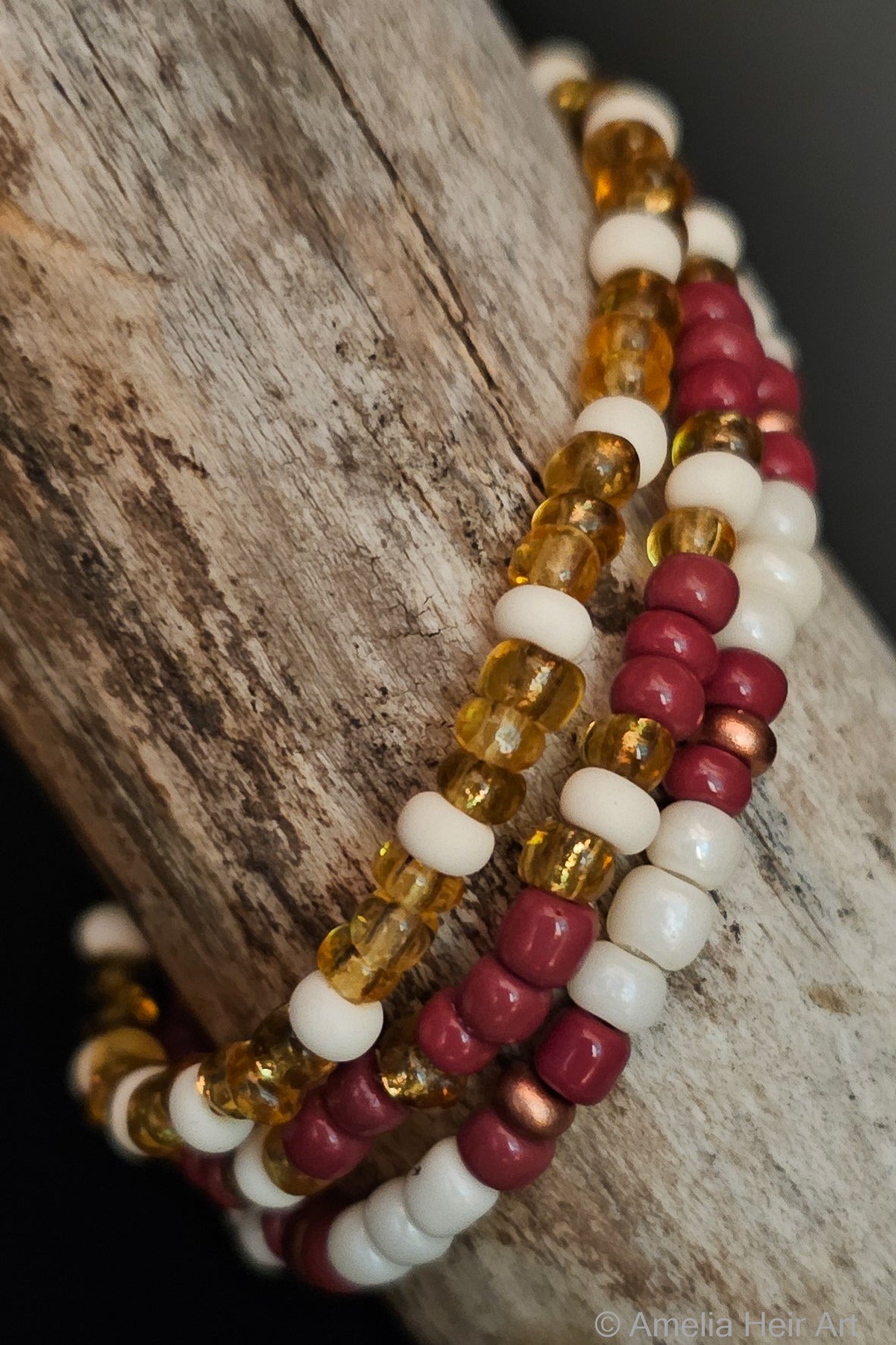 Three beaded bracelets in amber, brown, and cream on a wooden surface
