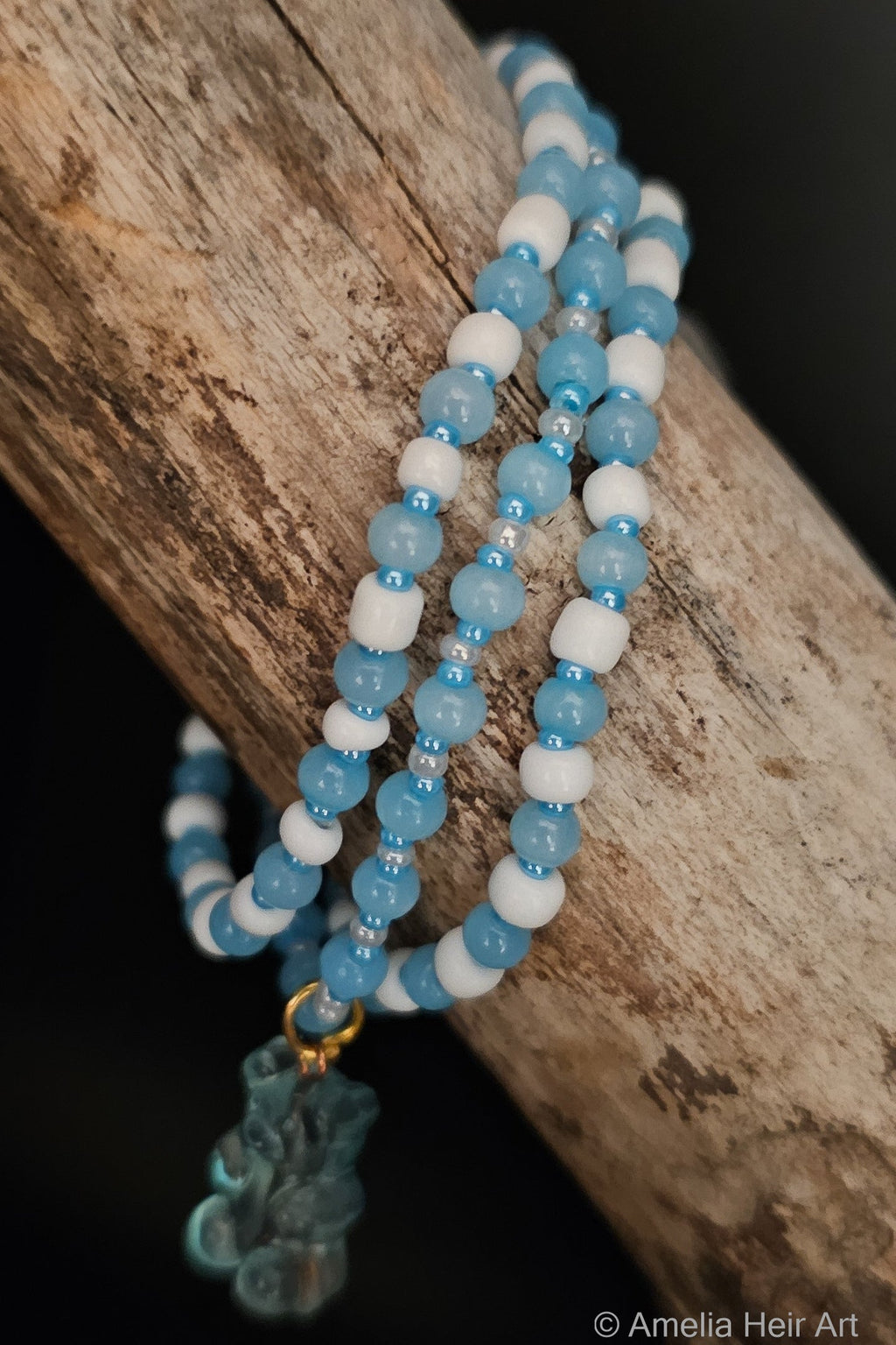 Blue and white beaded bracelet with a gummy-bear-shaped charm on a wooden branch