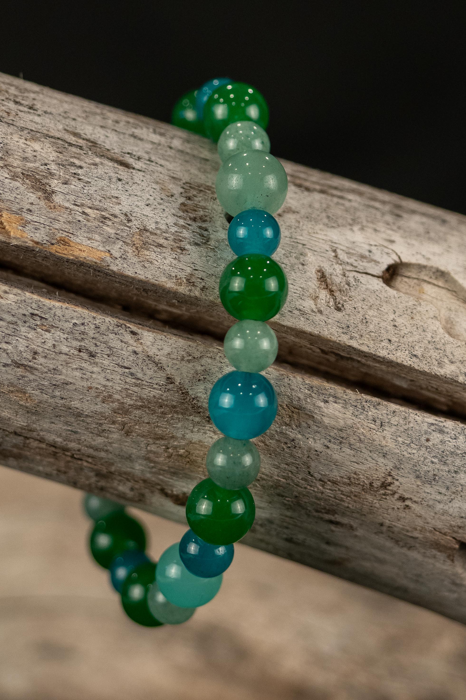 Beaded bracelet with green and blue beads on a wooden surface