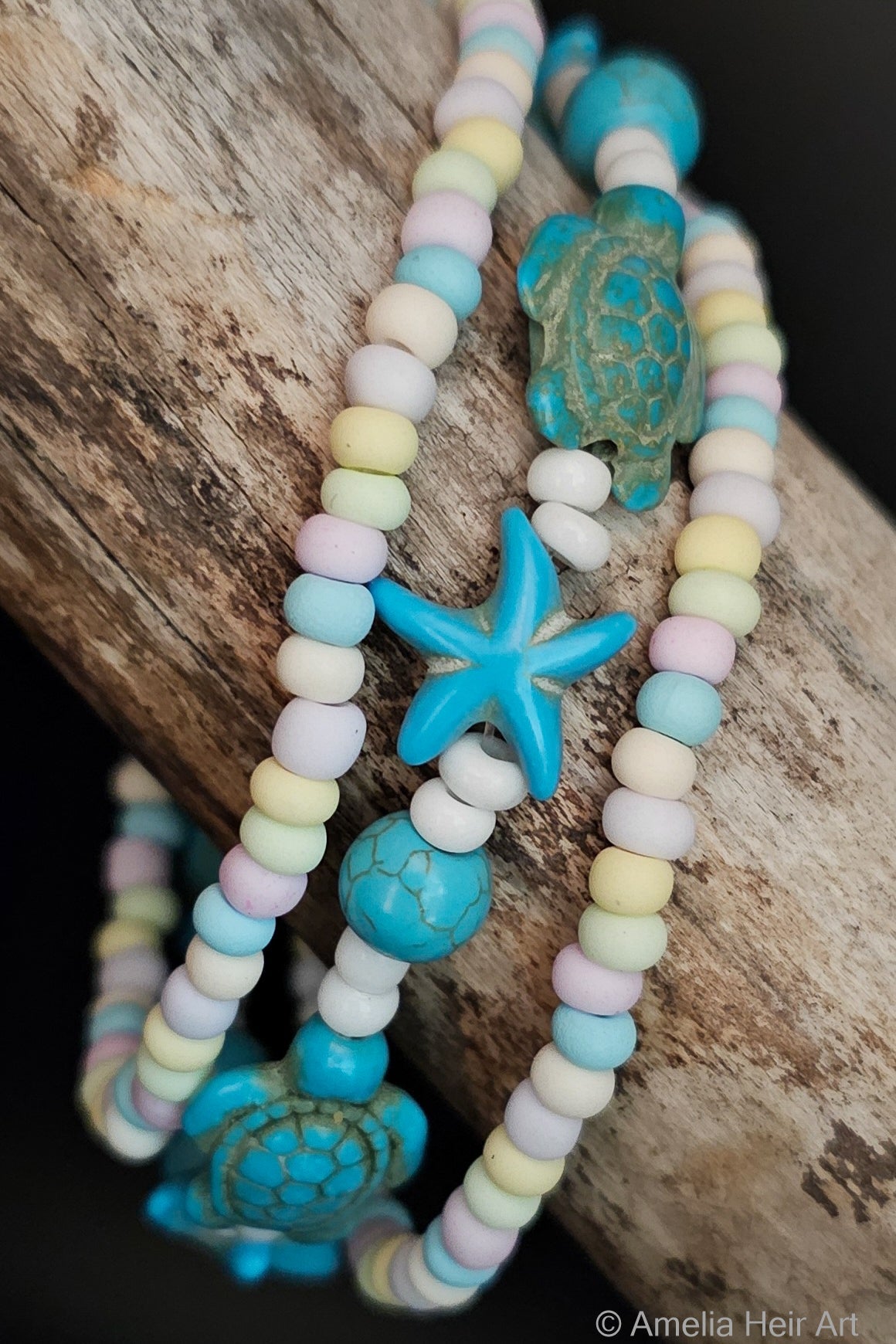 Pastel beaded bracelets with turquoise starfish and turtle beads on a wooden surface.