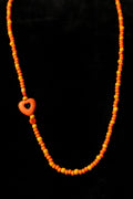 Necklace with orange beads and a heart-shaped bead on a black background
