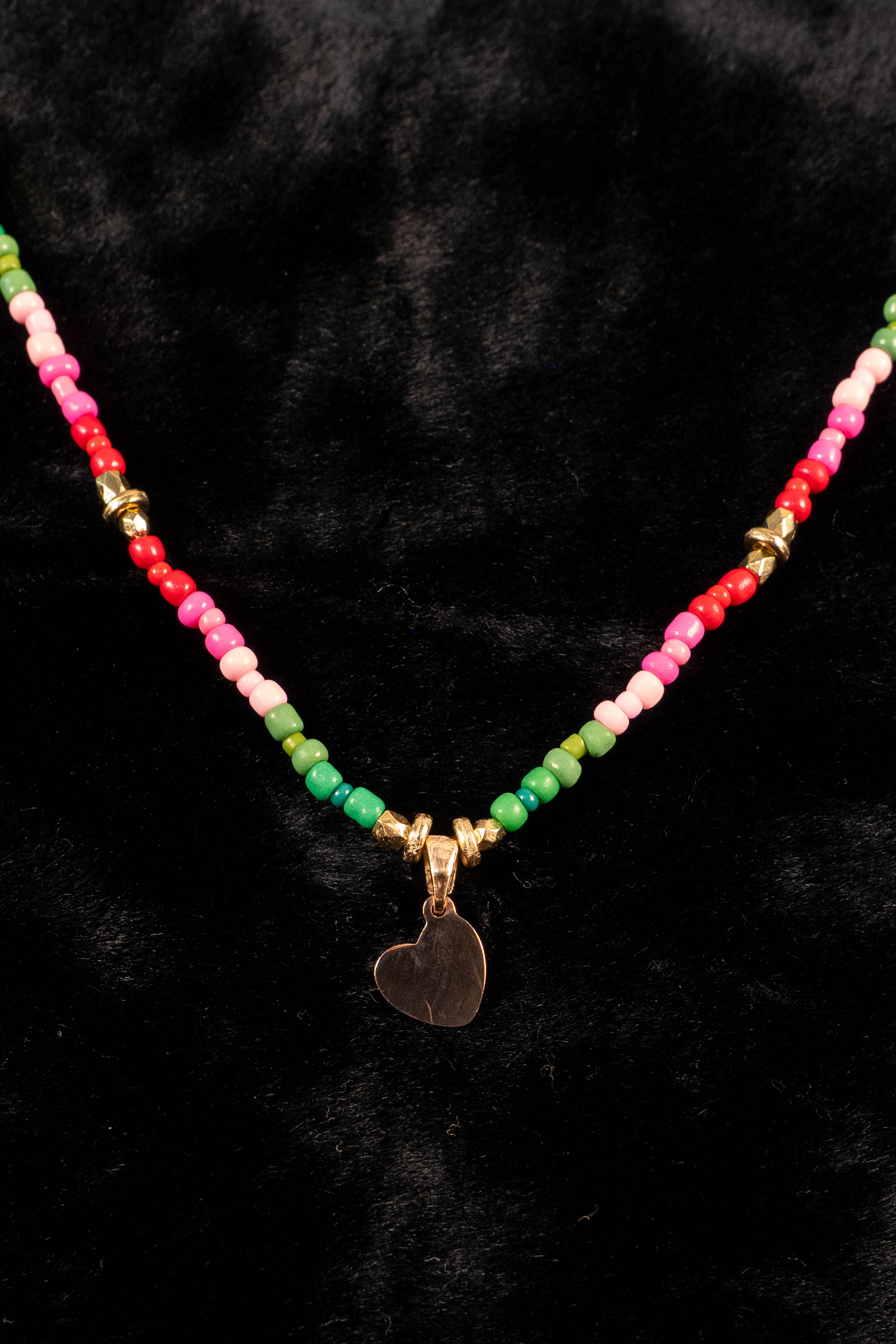 Necklace with colorful beads and a gold heart-shaped pendant on a black background