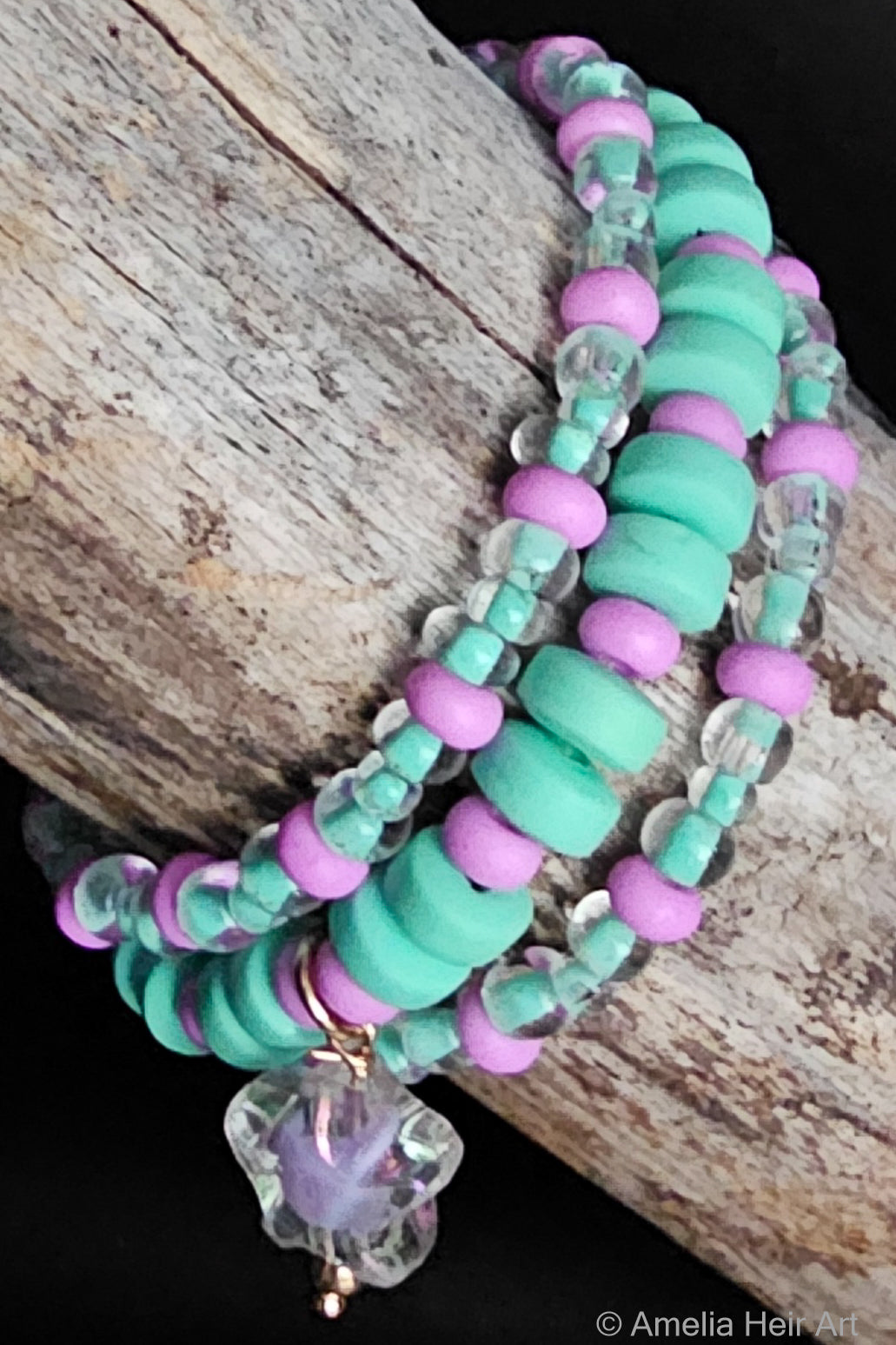 Stack of teel and purple beaded bracelets with a star-shaped charm on a wooden surface