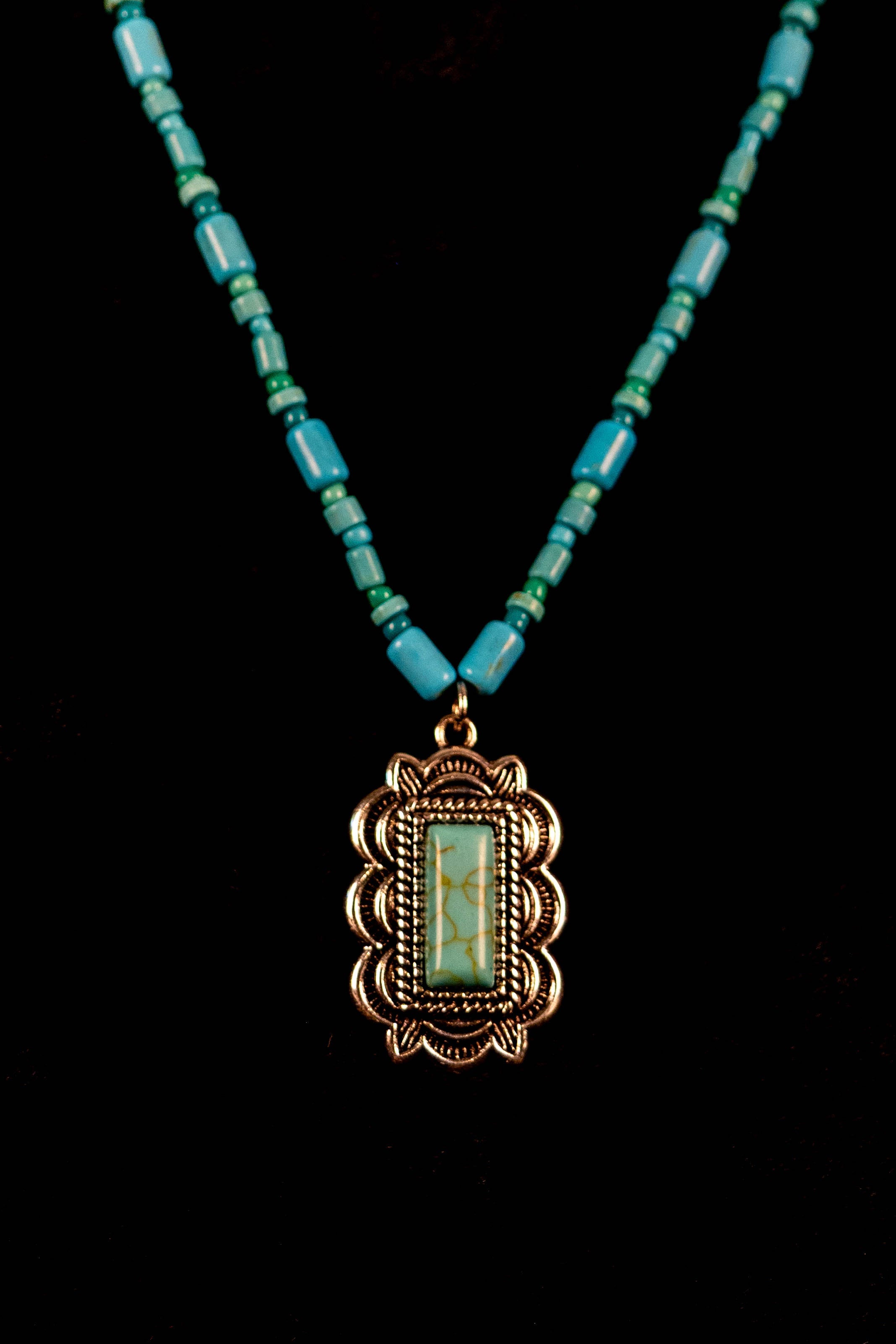 Necklace with turquoise beads and a decorative pendant on a black background
