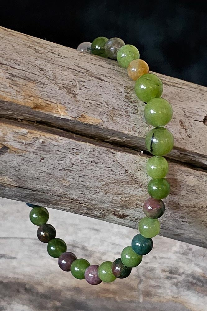 Greens and browns multicolored  beaded bracelet on a wooden surface