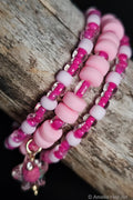 Pink and white beaded bracelets with a star-shaped charm on a wooden surface