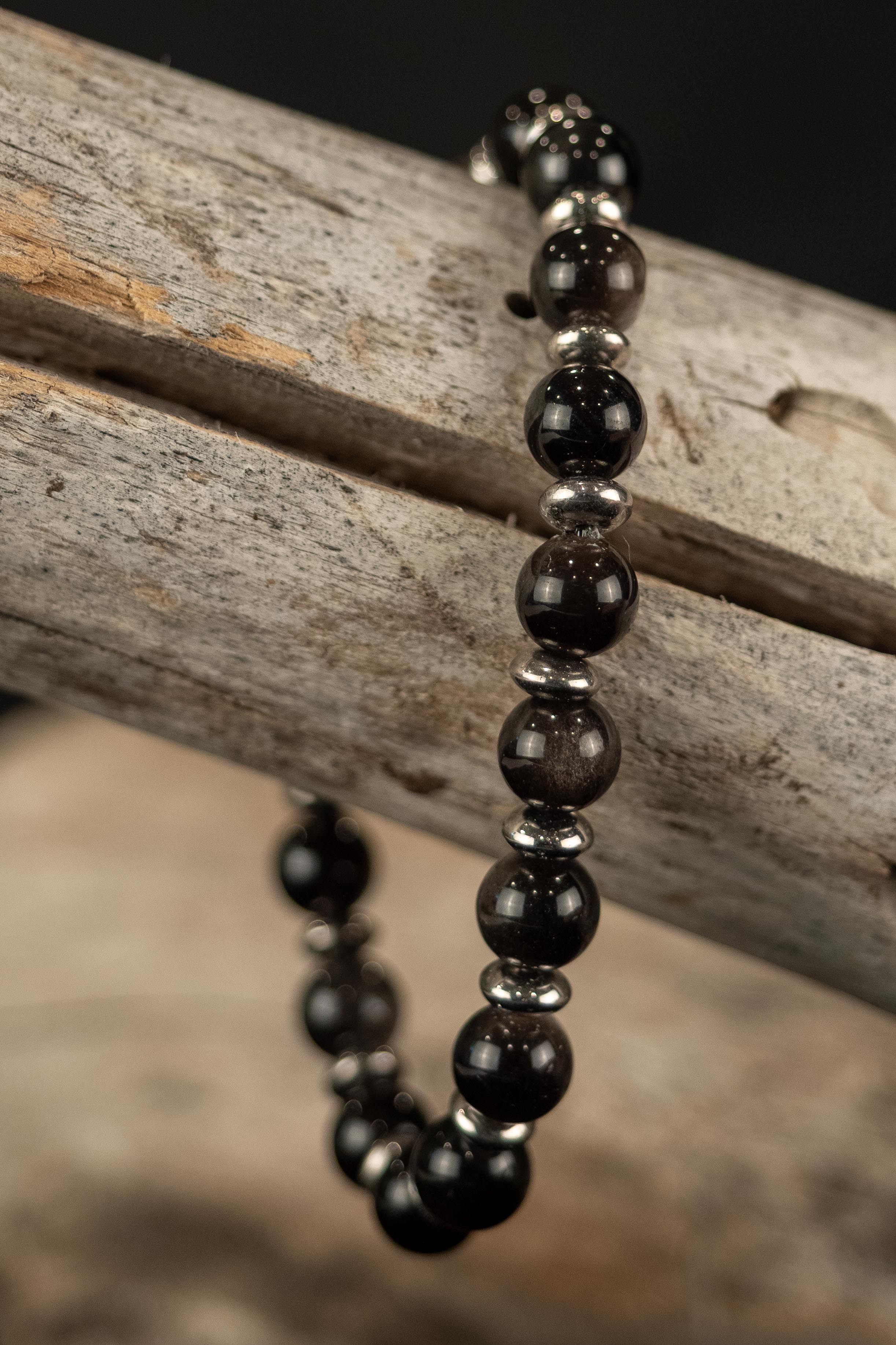 Beaded bracelet with black and silver beads on a wooden branch