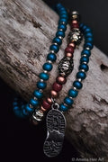 Beaded bracelets with metal boot print charm on a wooden surface