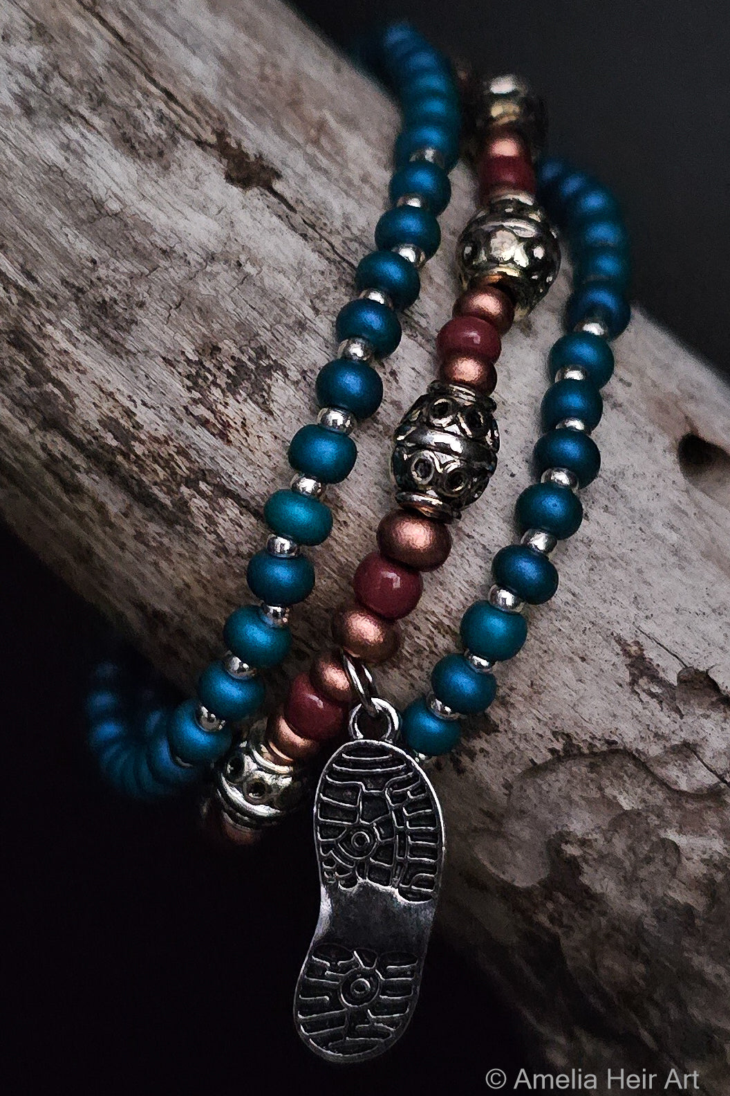 Beaded bracelets with metal boot print charm on a wooden surface