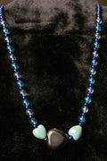 Necklace with blue beads and three heart-shaped beads on a black background