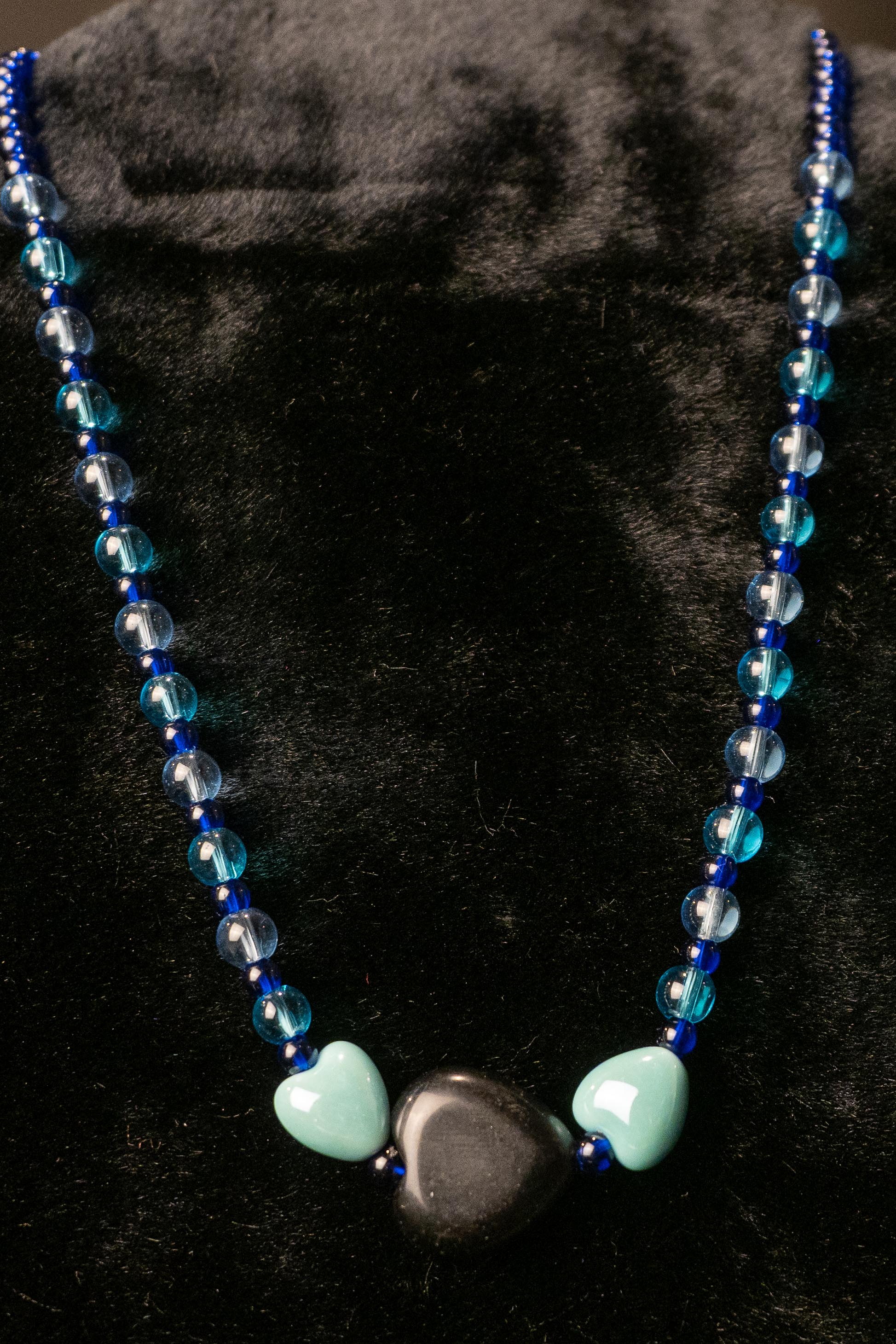 Necklace with blue beads and three heart-shaped beads on a black background