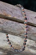 Bracelet with gray and orange beads on a wooden surface