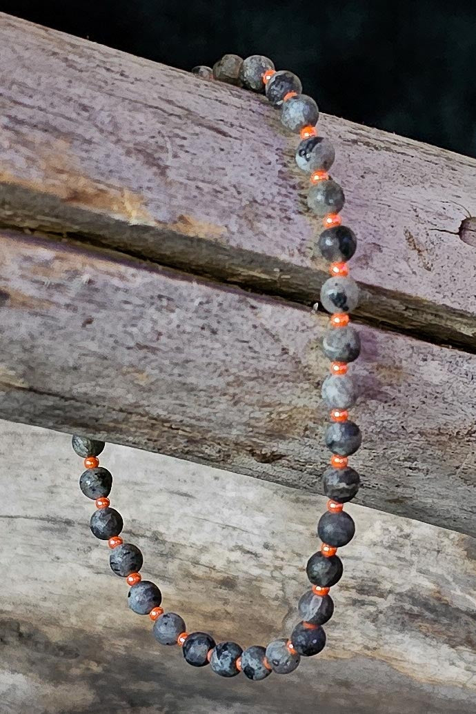 Bracelet with gray and orange beads on a wooden surface