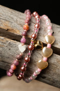 Three beaded bracelets with heart-shaped beads and charm on a wooden surface