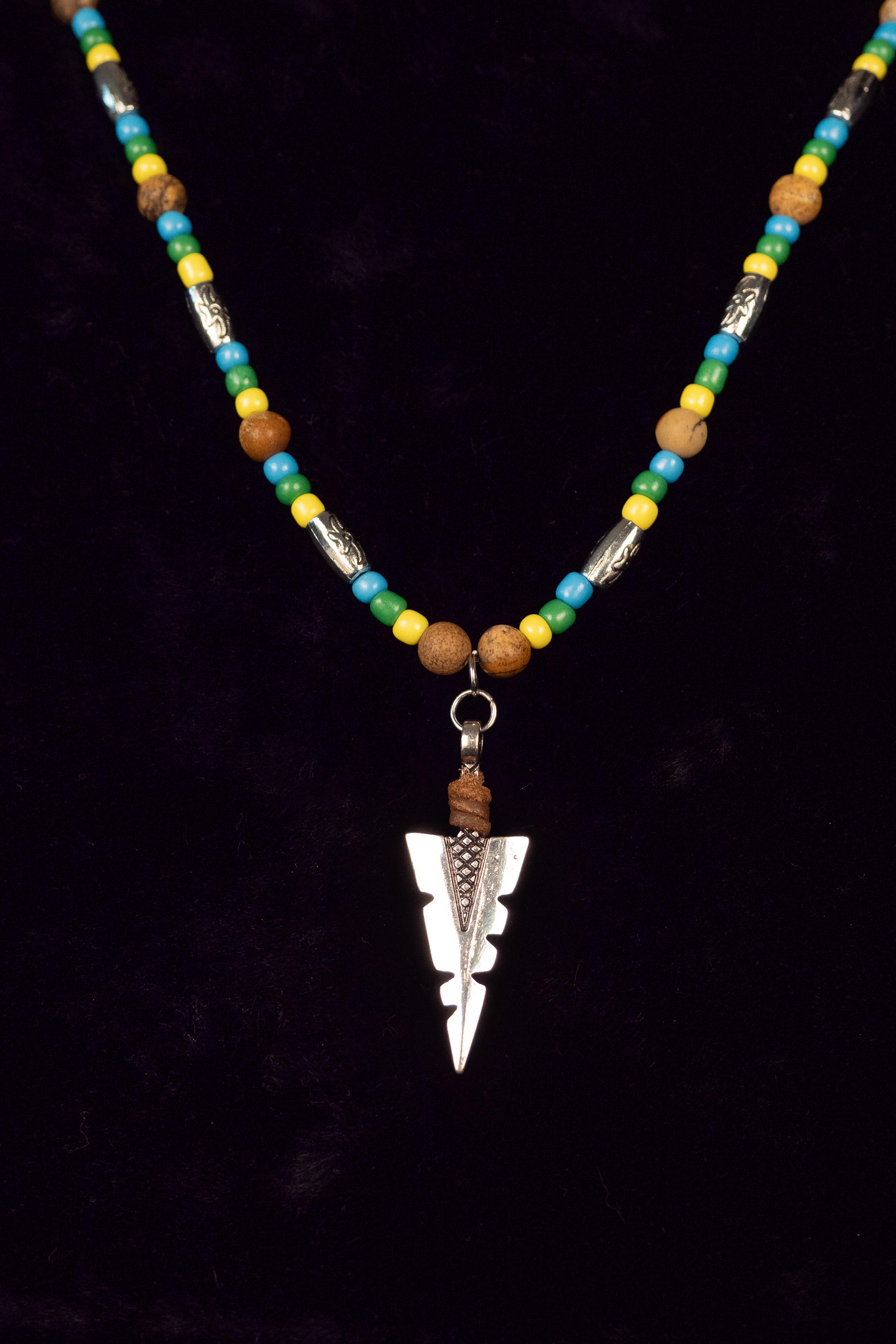 Necklace with beads and a silver arrowhead pendant on a black background