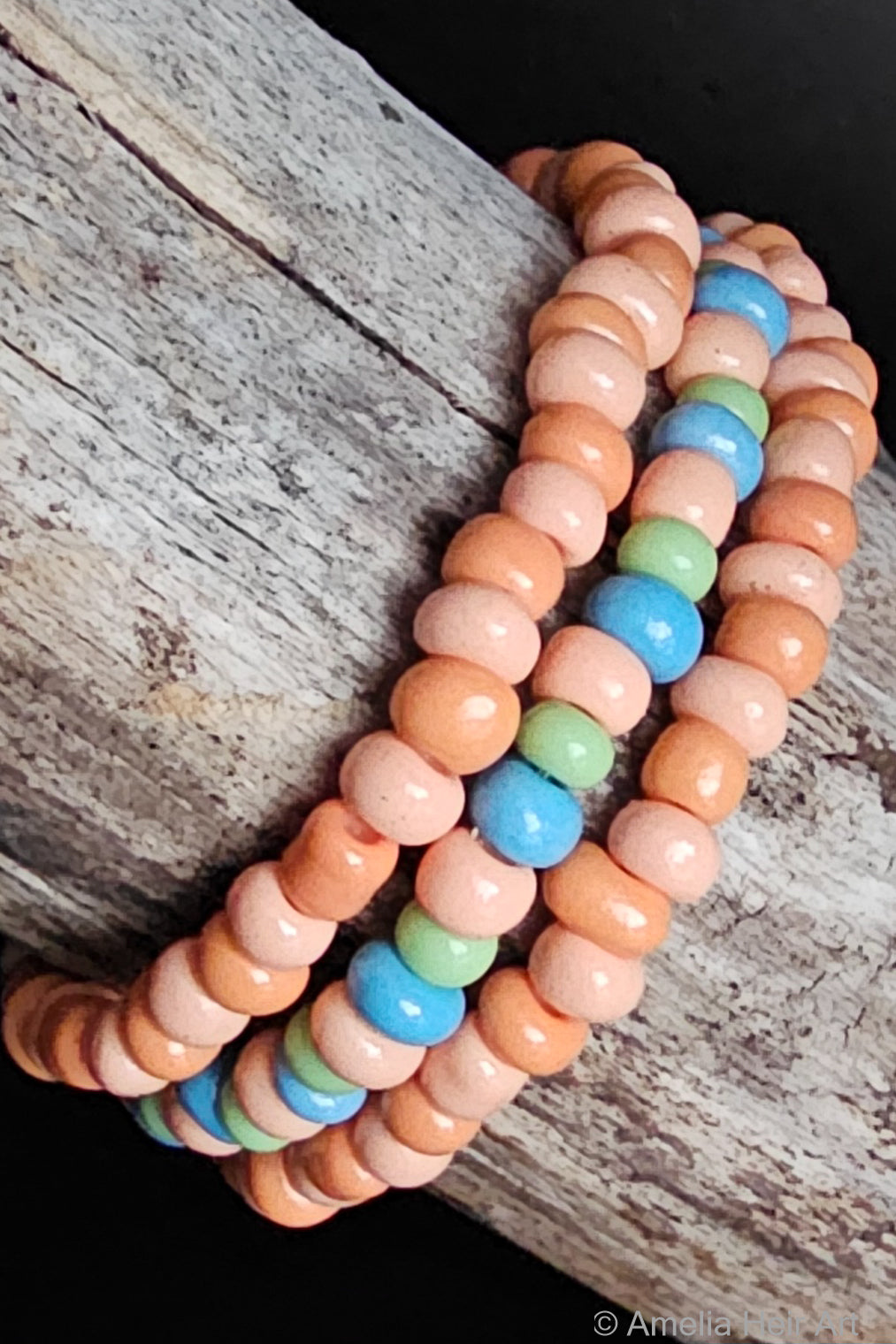 Stack of colorful beaded bracelets on a wooden surface