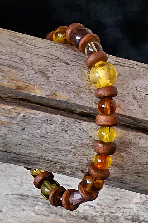 Beaded bracelet with brown, amber, and clear beads on a wooden surface