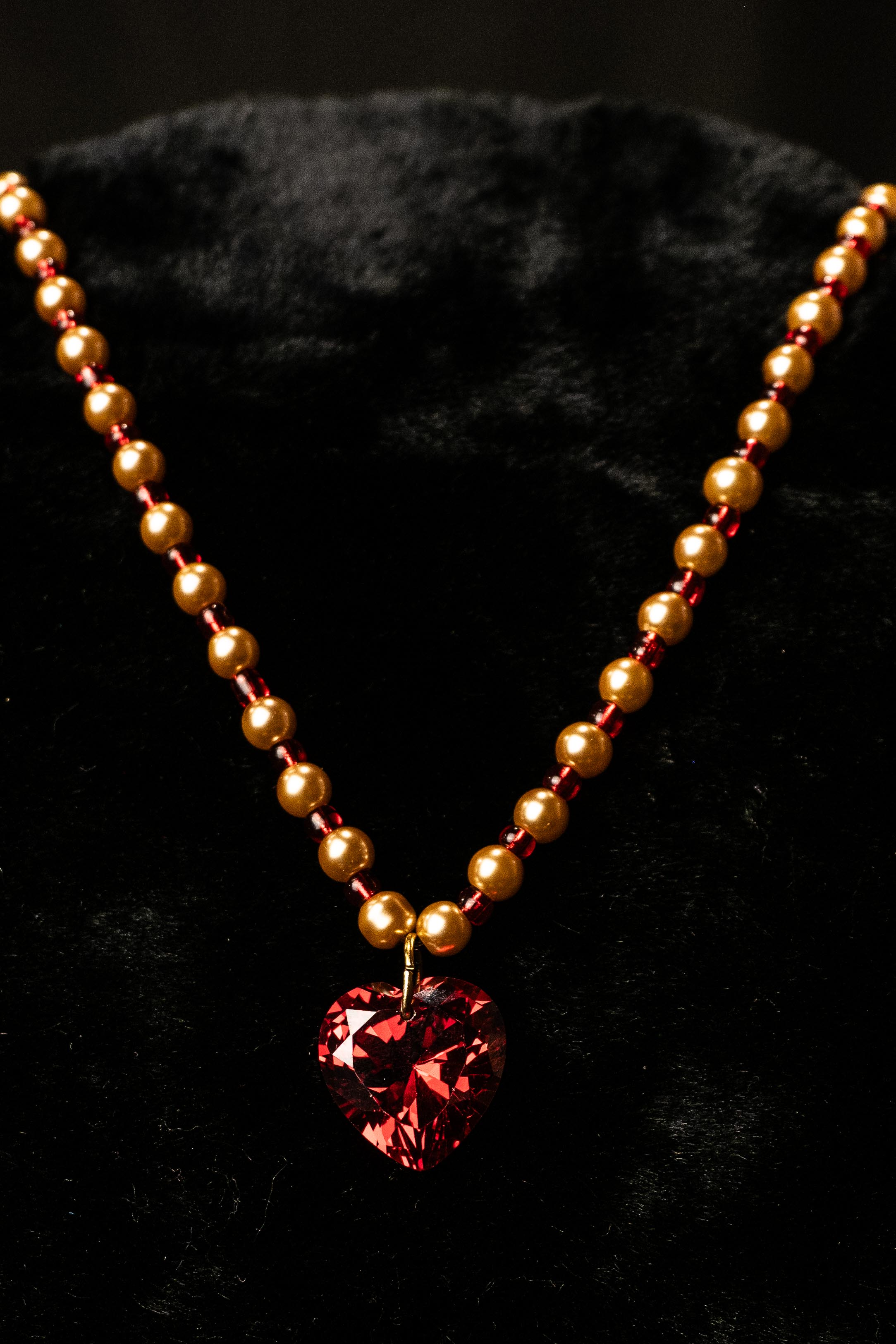 Necklace with multi-faceted red heart pendant on a black background