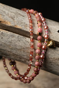 Three pink, clear, and purple beaded bracelets with a small heart-shaped charm on a wooden surface