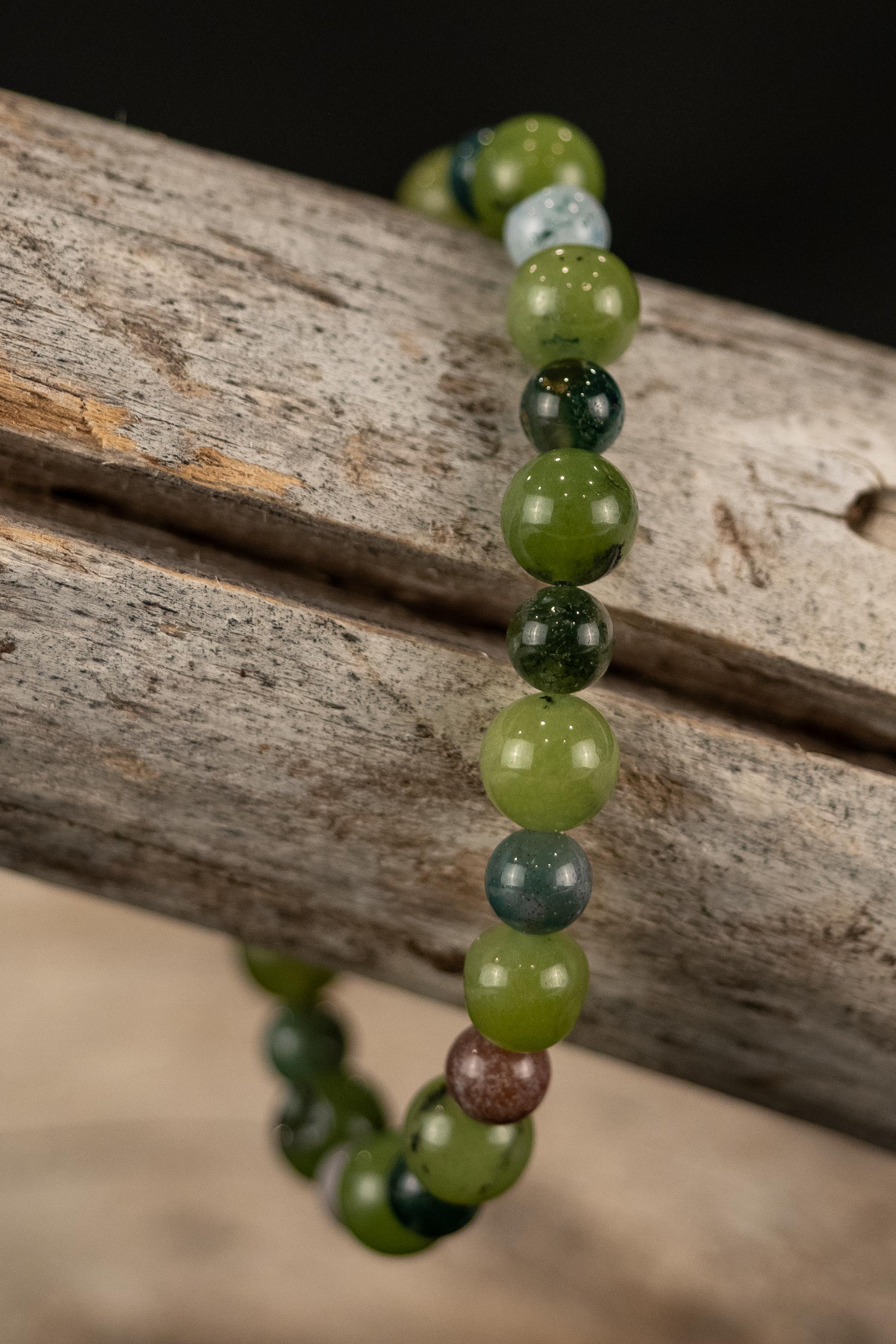 Beaded bracelet with green and brown beads on a wooden surface