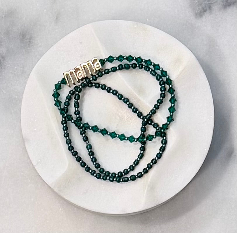 Three strand dark green beaded crystal and glass stretch bracelet set with a gold 'mama' metal statement bead on a stone marble surface — Amelia Heir Art