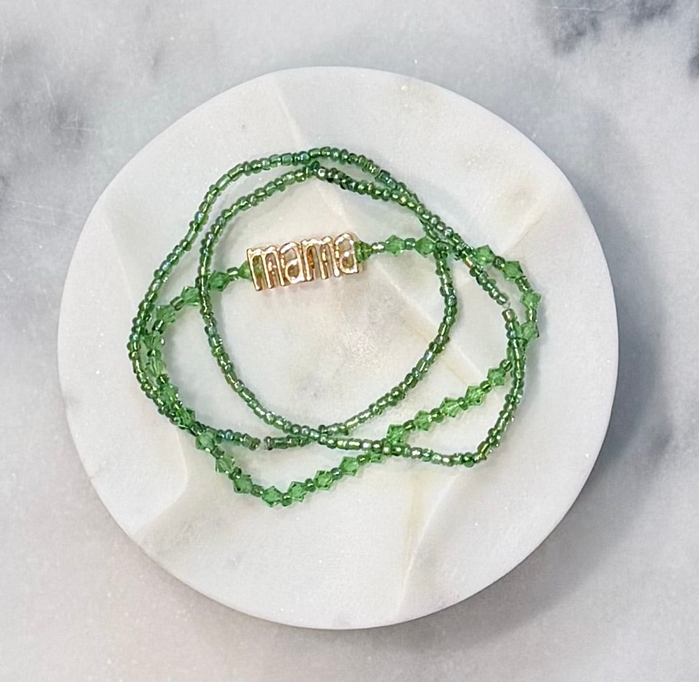 Three strand light green beaded crystal and glass stretch bracelet set with a gold 'mama' metal statement bead on a stone marble surface — Amelia Heir Art