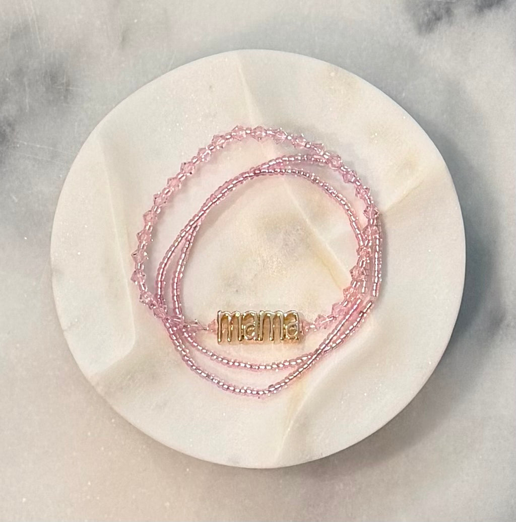Three strand pink beaded crystal and glass stretch bracelet set with a gold 'mama' metal statement bead on a stone marble surface — Amelia Heir Art