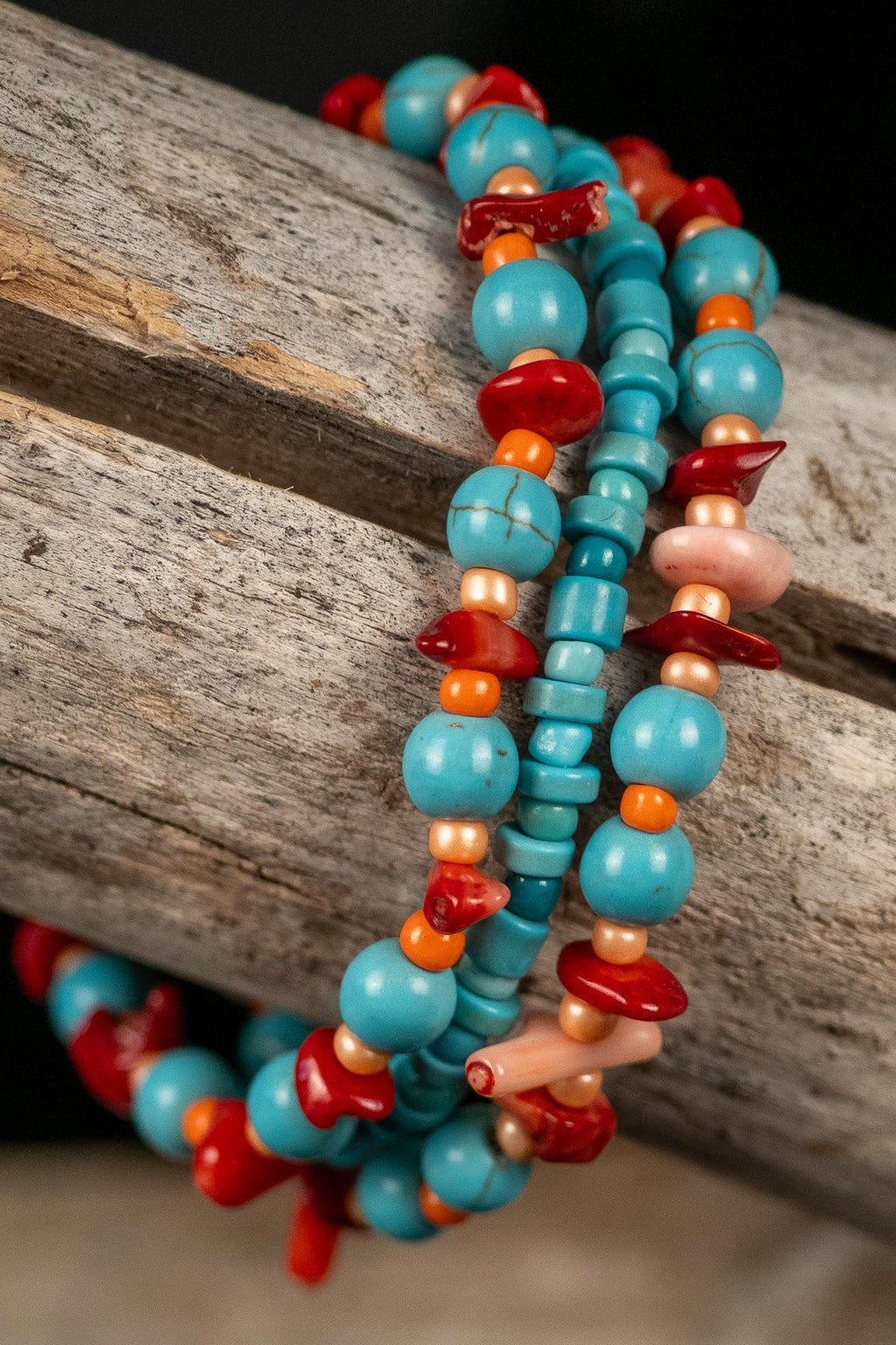 Red, orange, and turquois color beaded bracelets on a wooden surface