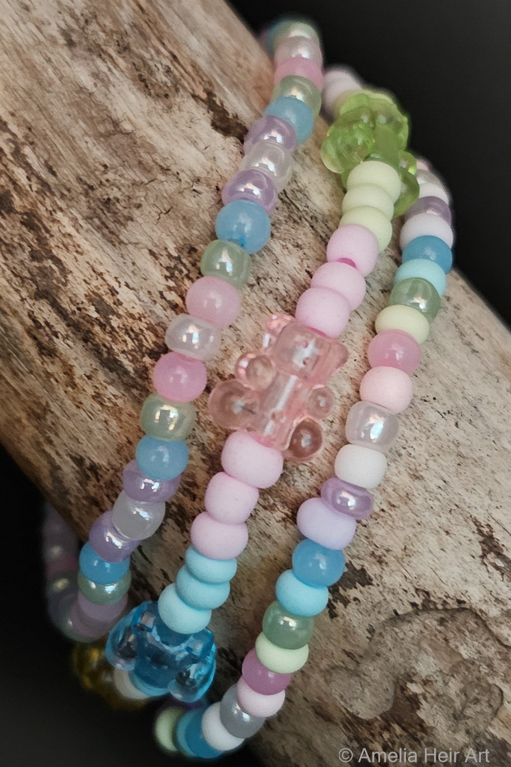 Pastel beaded bracelets with gummy-bear-shaped beads on a wooden surface