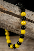 Black and yellow beaded bracelet on a wooden surface