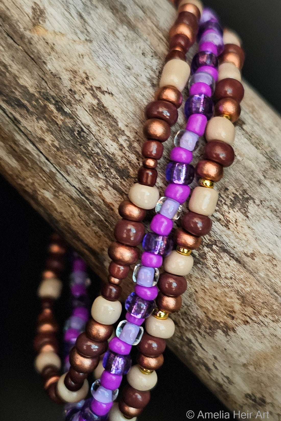 Beaded bracelets with purple, brown, and beige beads on a wooden surface.