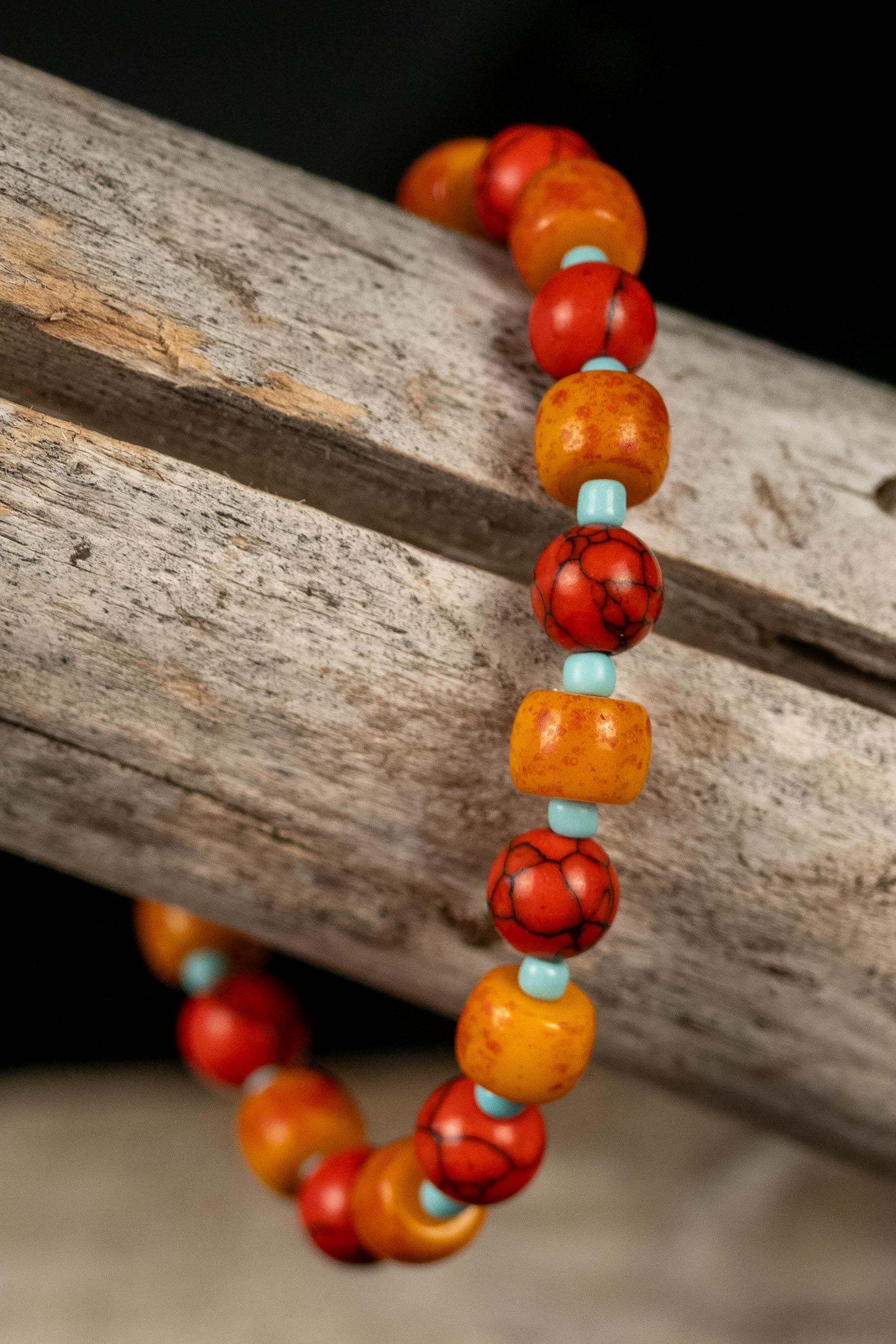 Necklace with red, orange, and turquoise color beads on a wooden surface