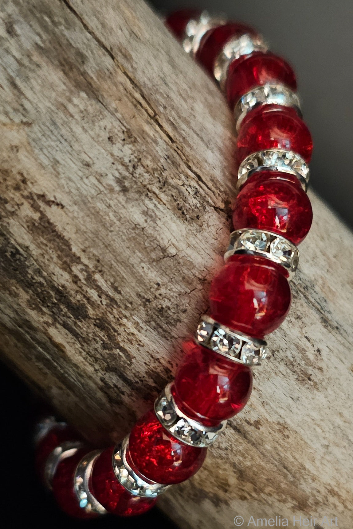 Red beaded bracelet with silver accents on a wooden surface