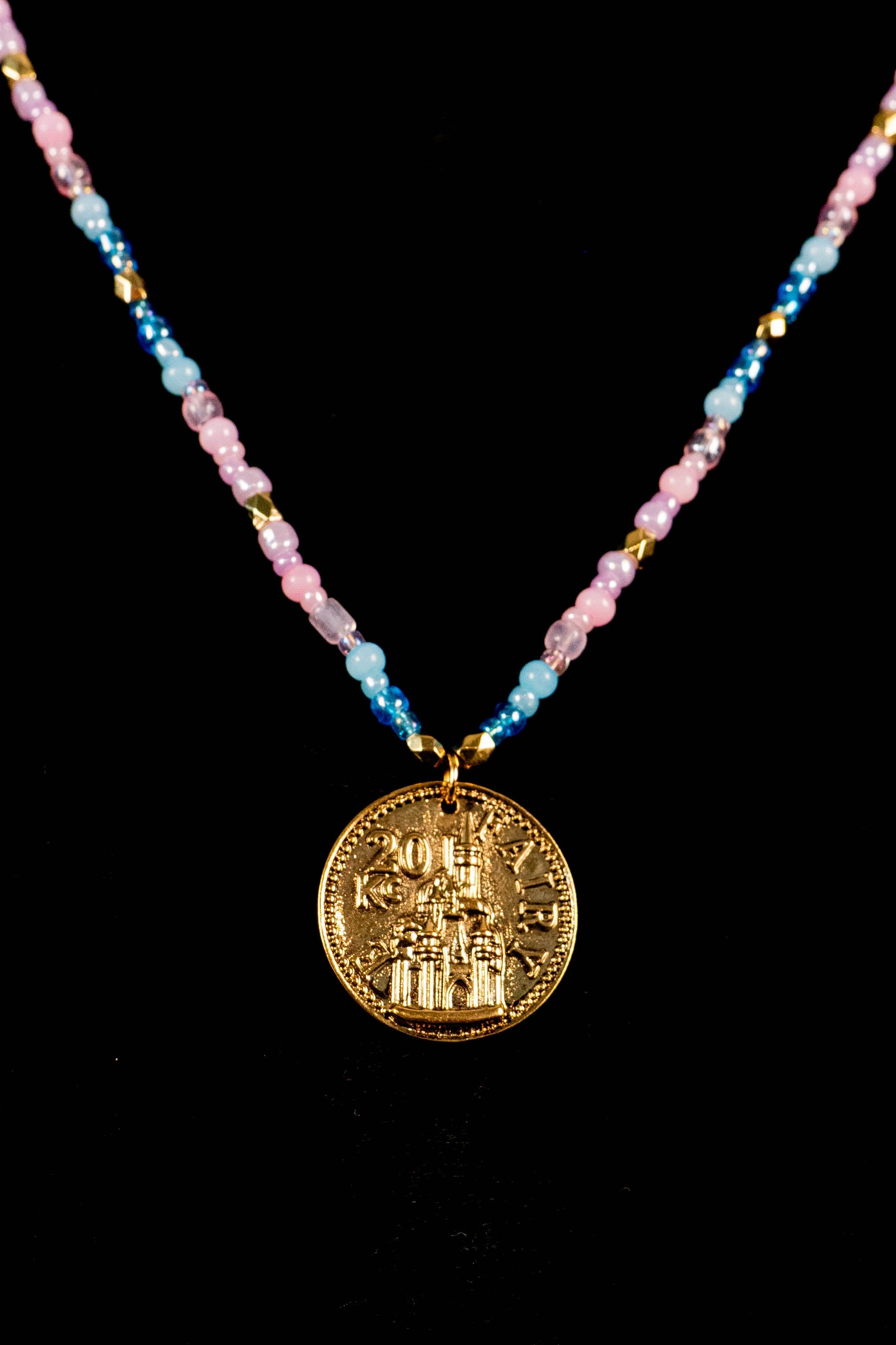 Necklace with a gold coin castle pendant and multicolored beads on a black background